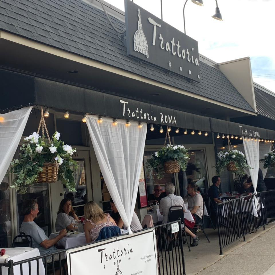 the outdoor dining area of trattoria's in upper arlingdonw, draped with white curtains and hanging baskets overflowing with white flowers