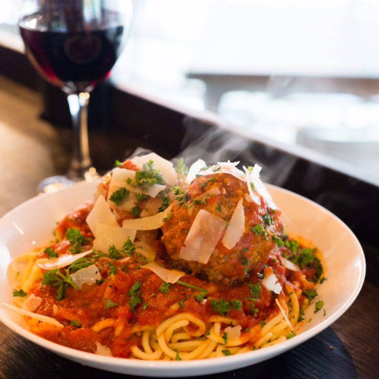 warm spaghetti and meatballs sits beside a glass of red white at one of upper arlington's best italian restaurants
