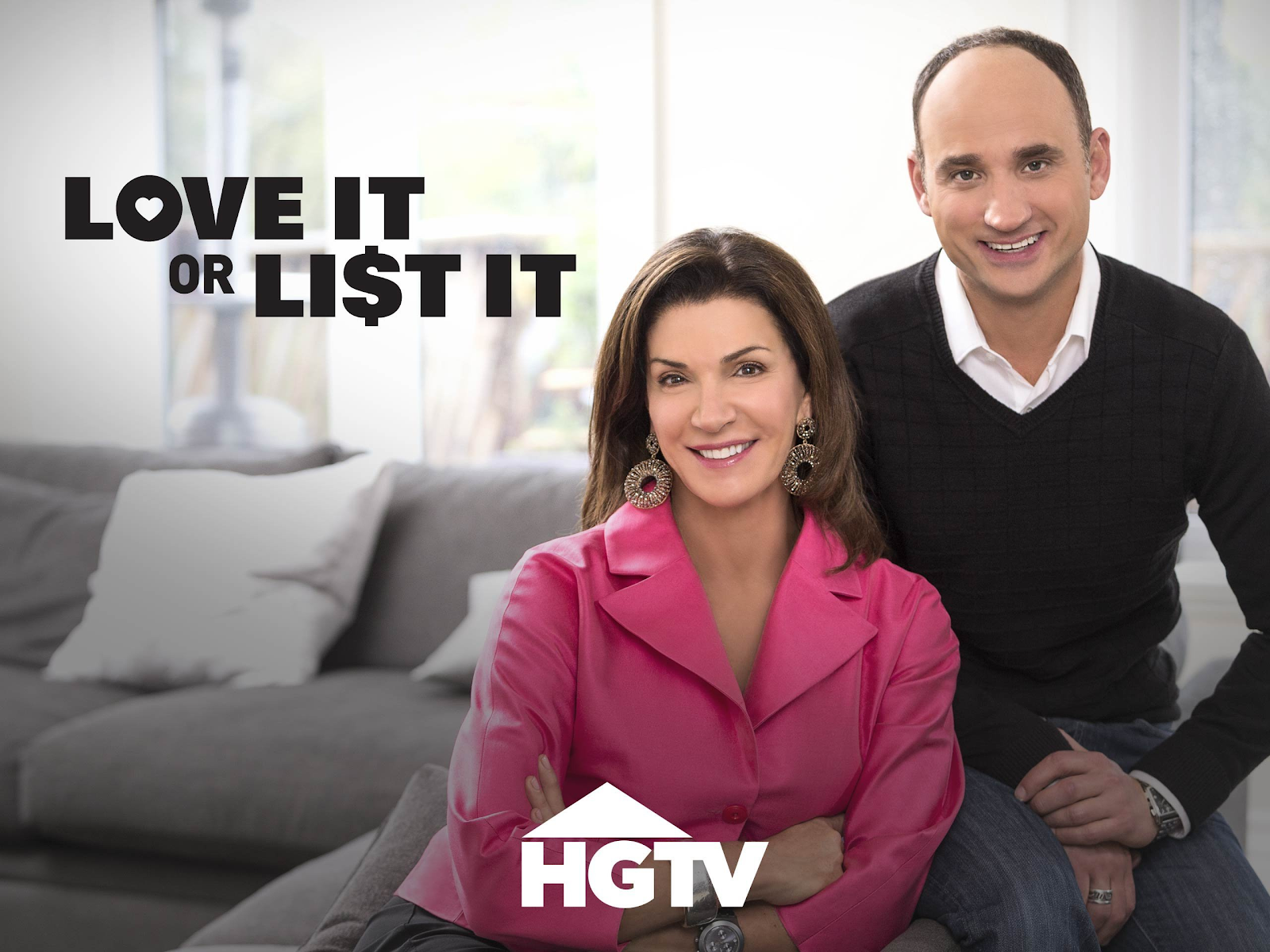 Hilary Farr and David Vesentin sit side by side smiling on a couch