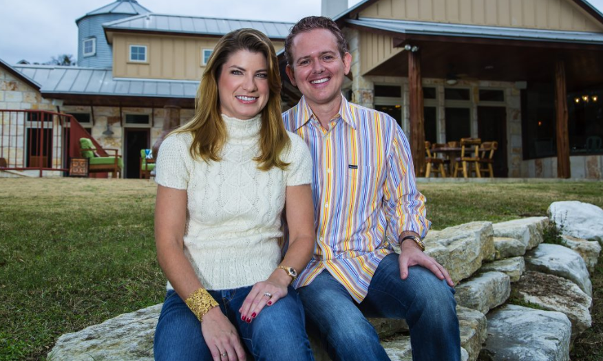 Tim and Julie Harris sit and smile outdoors in front of an industrial-looking country home