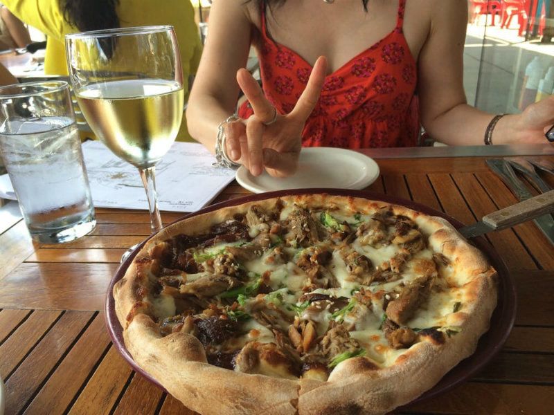 A woman at a table with wine and pizza at SPAGIO