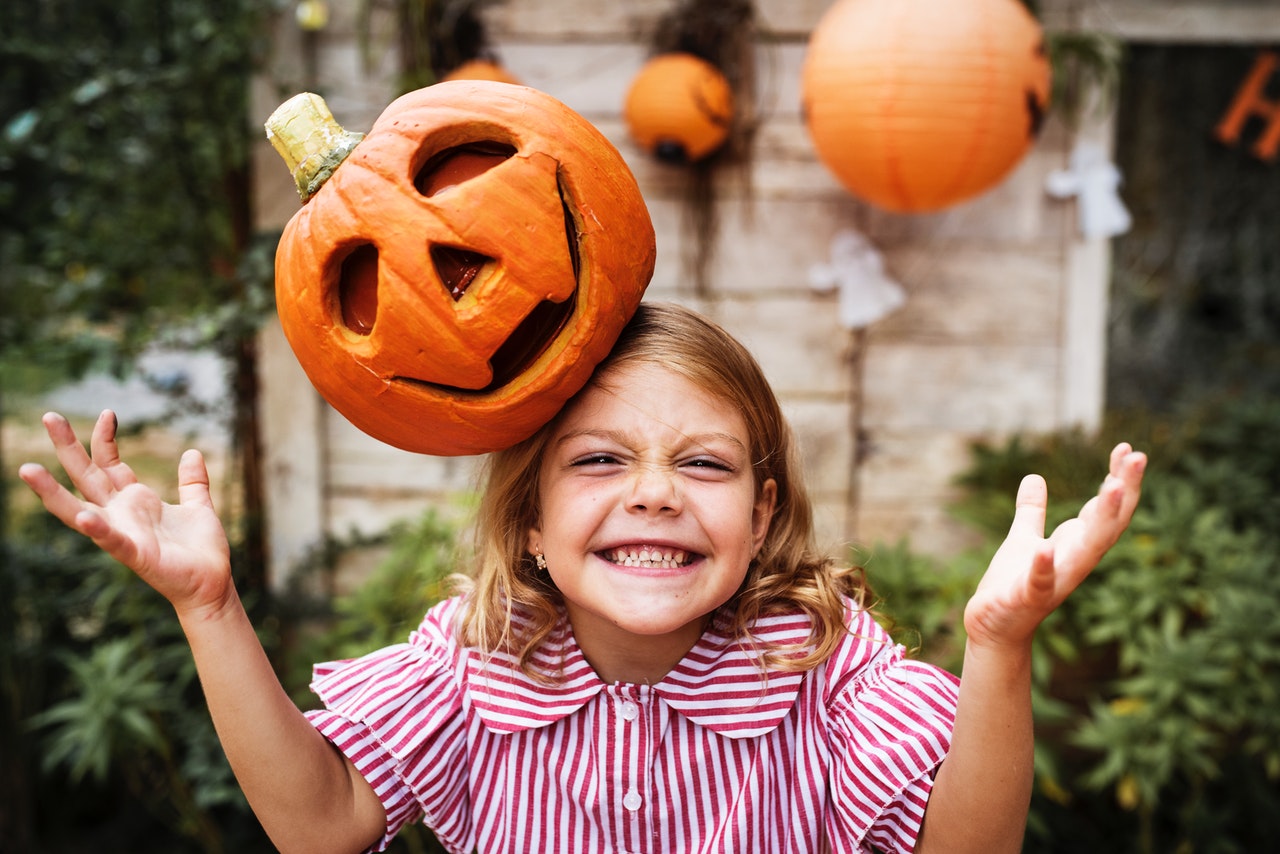 a young girl with a jack o lantern on her head as part of a halloween costume