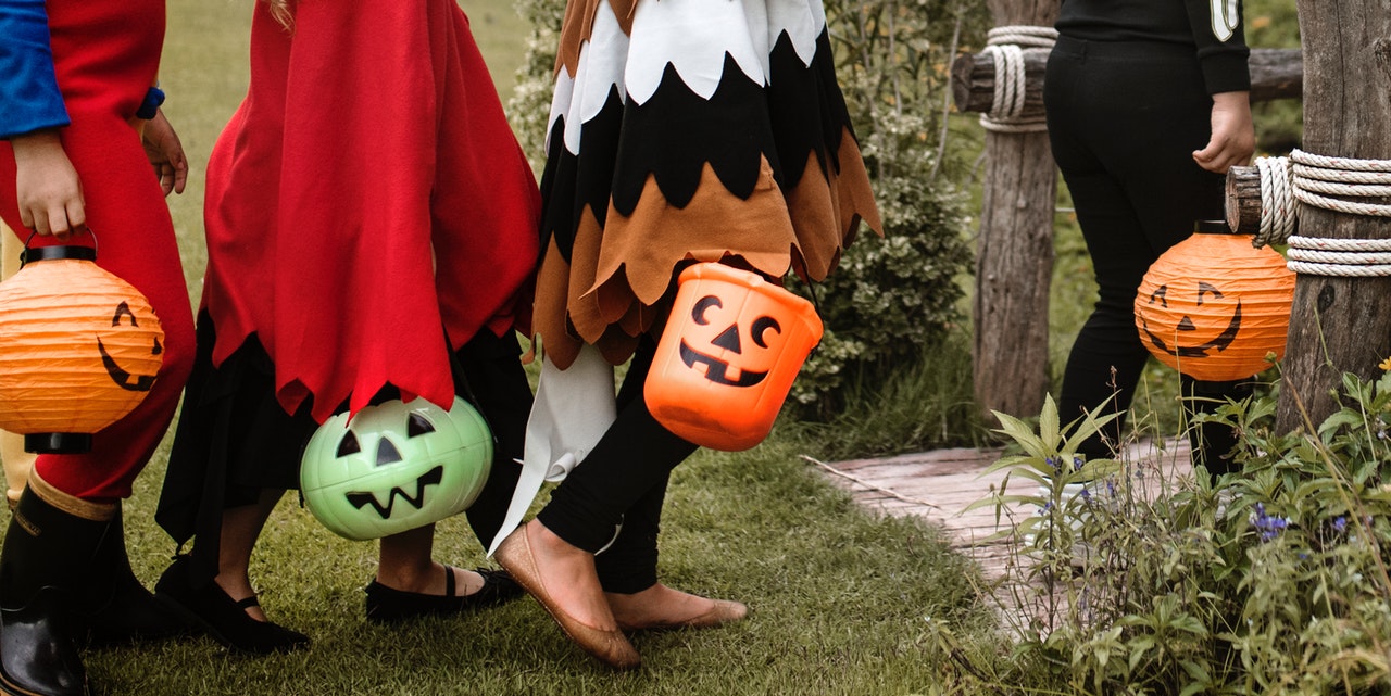 Children holding candy pails shaped like jack-o-lanterns march towards their trick-or-treats