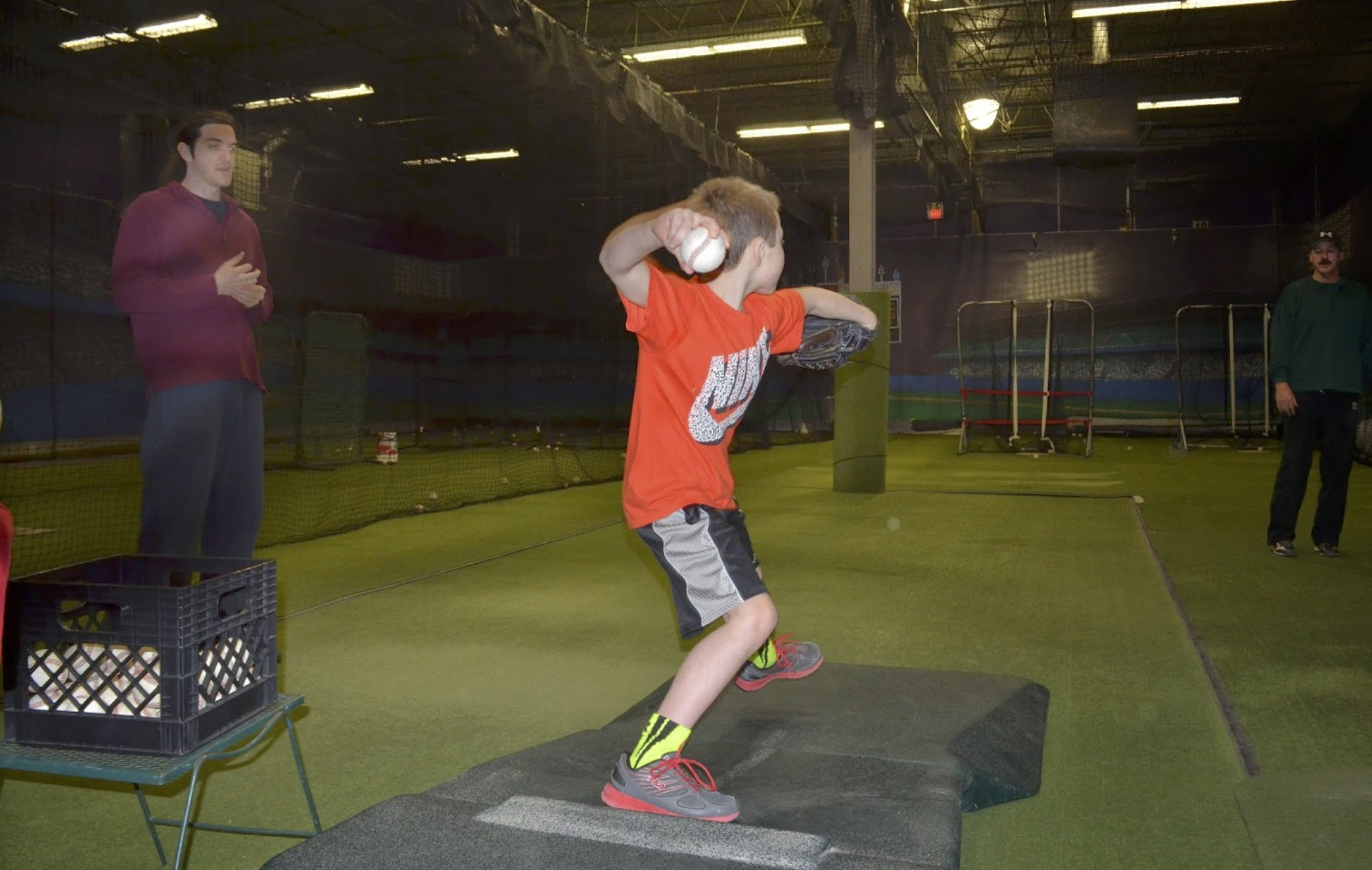 Coaches watch as young boy practices pitching