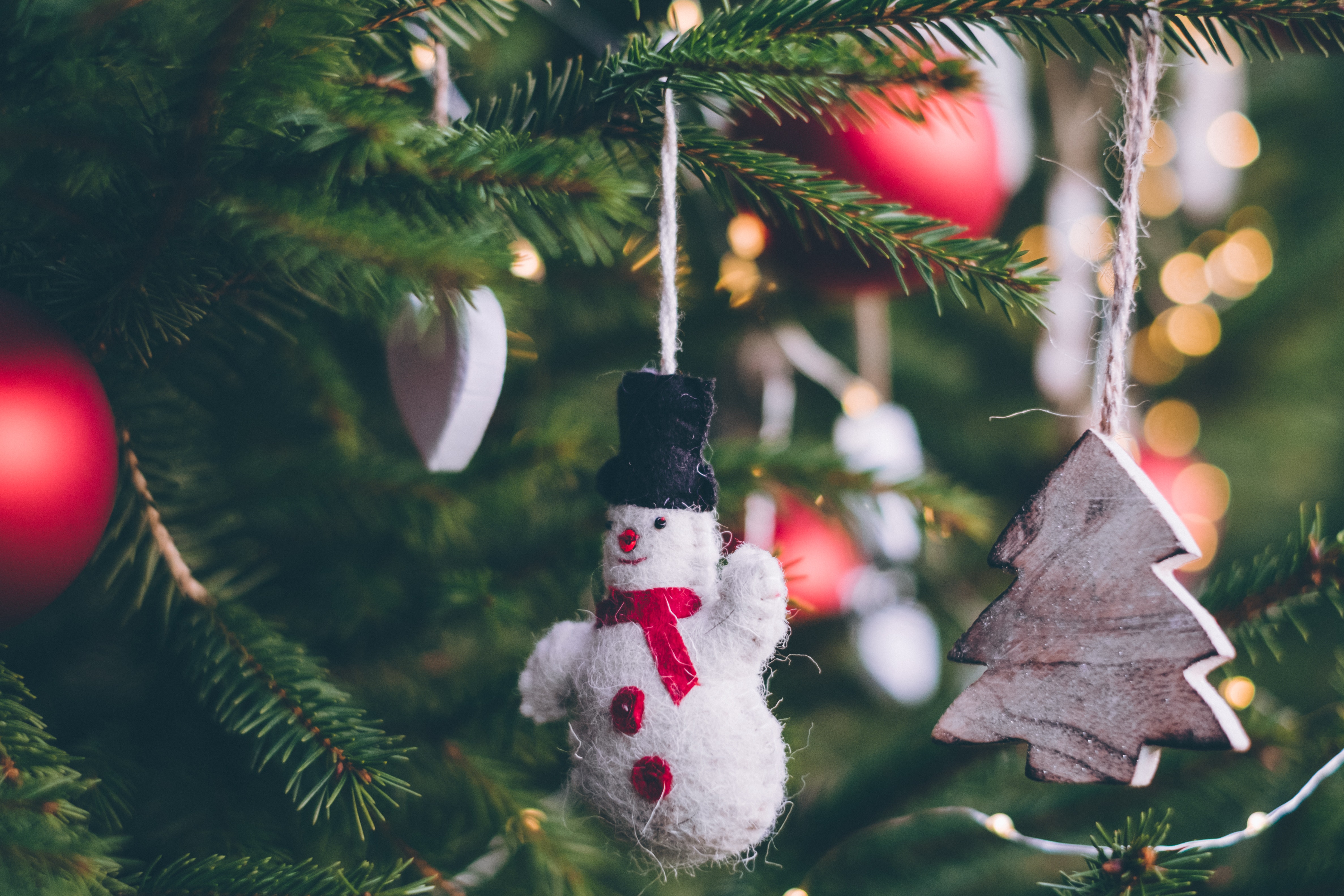 Snowman hanging from a tree with red ornaments