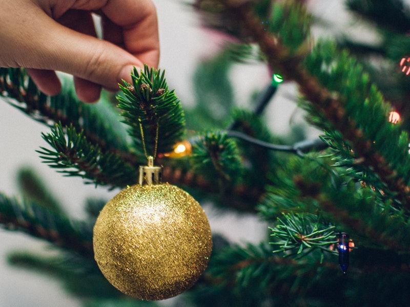 person hanging ornament on the tree