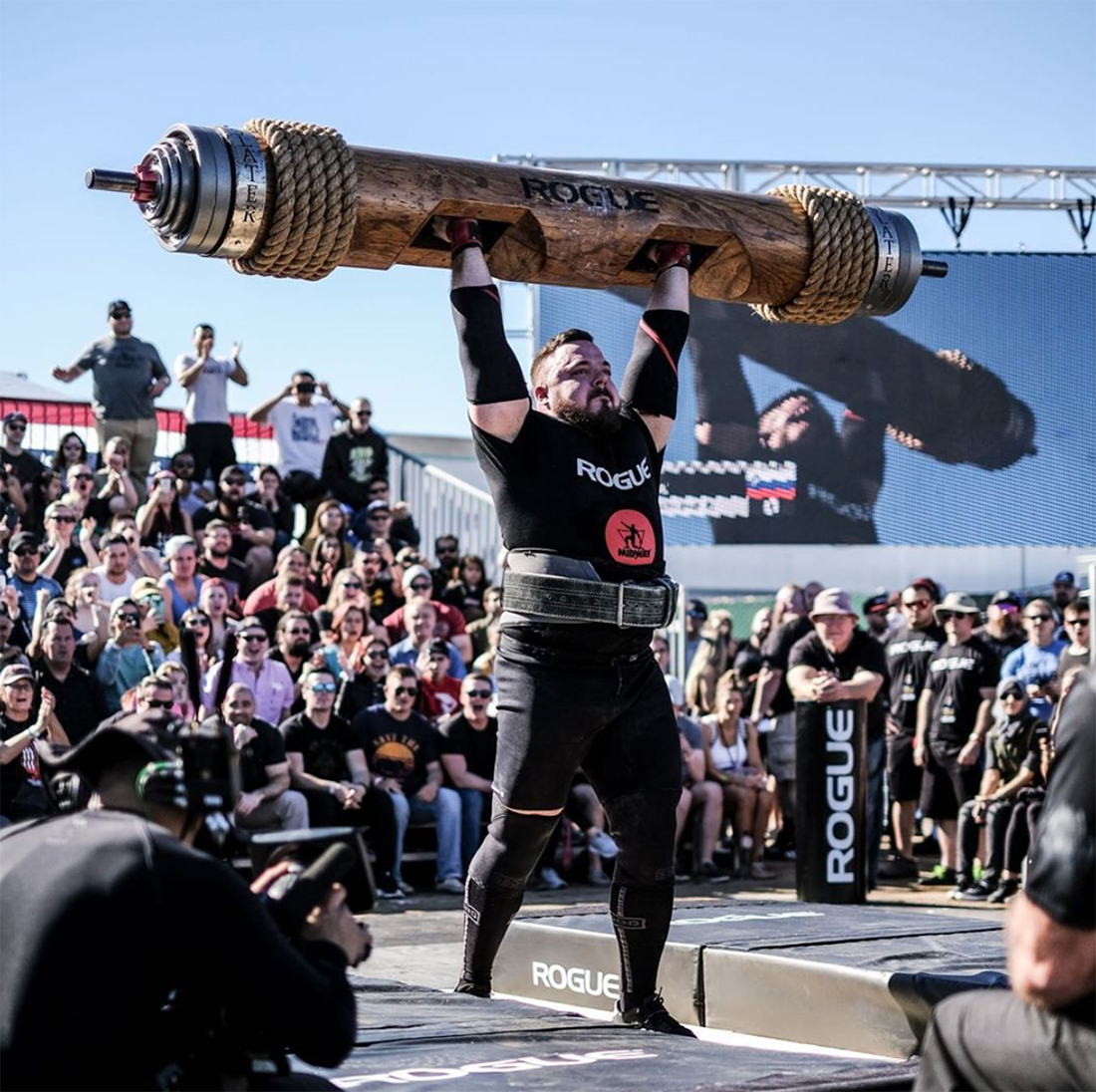 Strong man lifting heavy weights in front of a crowd