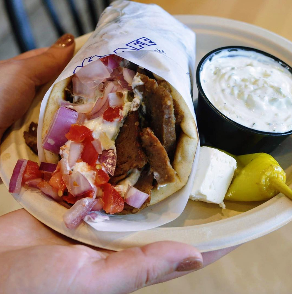 A gyro on a plate with pepper and tatziki