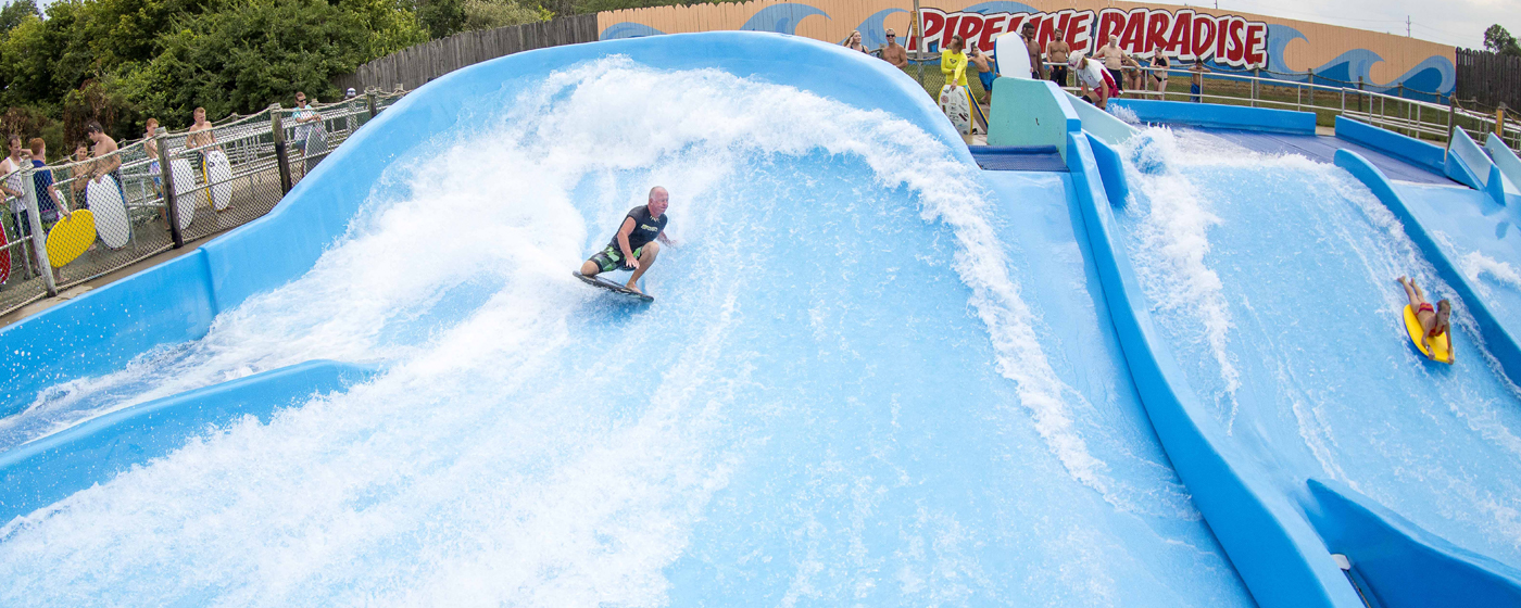 A man is boady board surfing on a large water slide