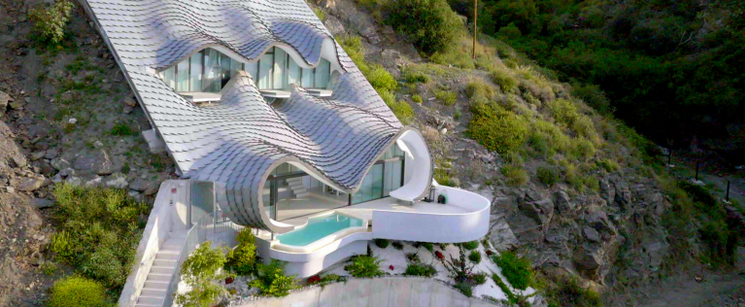 A white house with a pool built into a mountain.