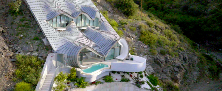 A white house with a pool built into a mountain. 