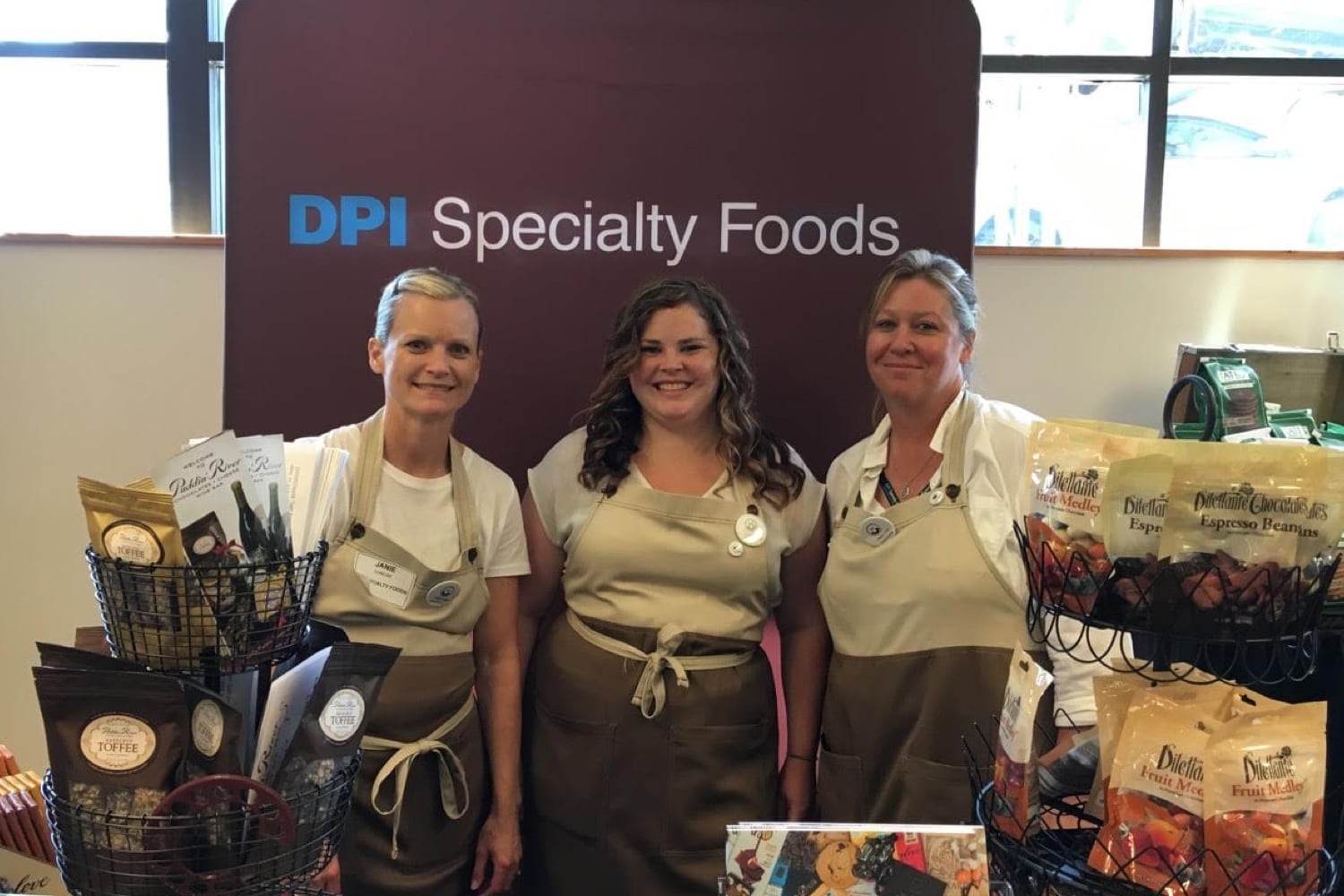 Group of three DPI Specialty Foods employees at their trade show booth