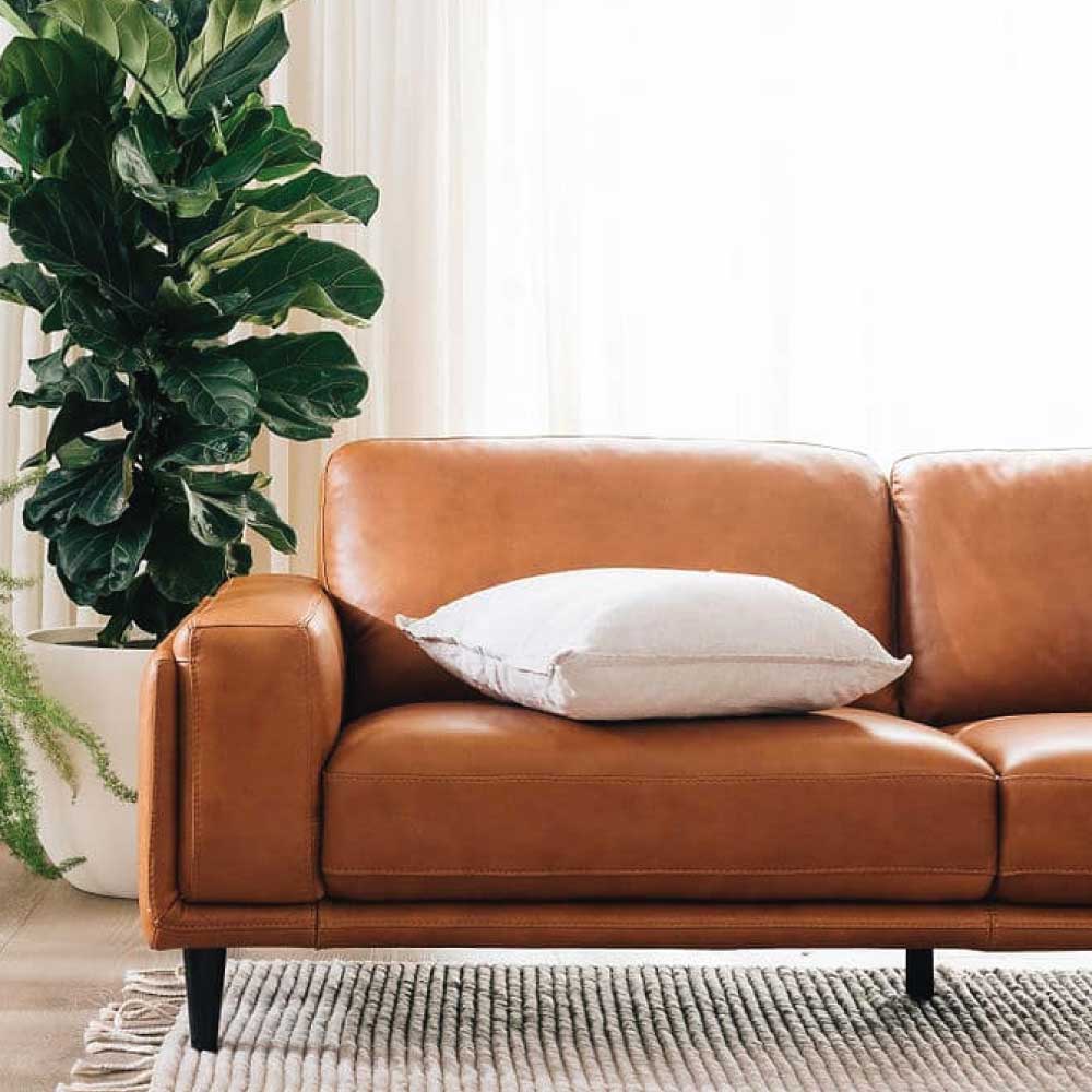 Plush brown leather sofa with white cushion