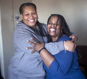 dos mujeres sonriendo y abrazando