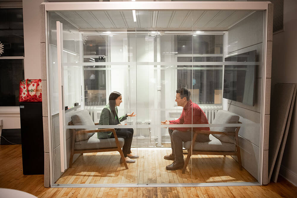 Photo of two Mighty staff talking in a glass booth