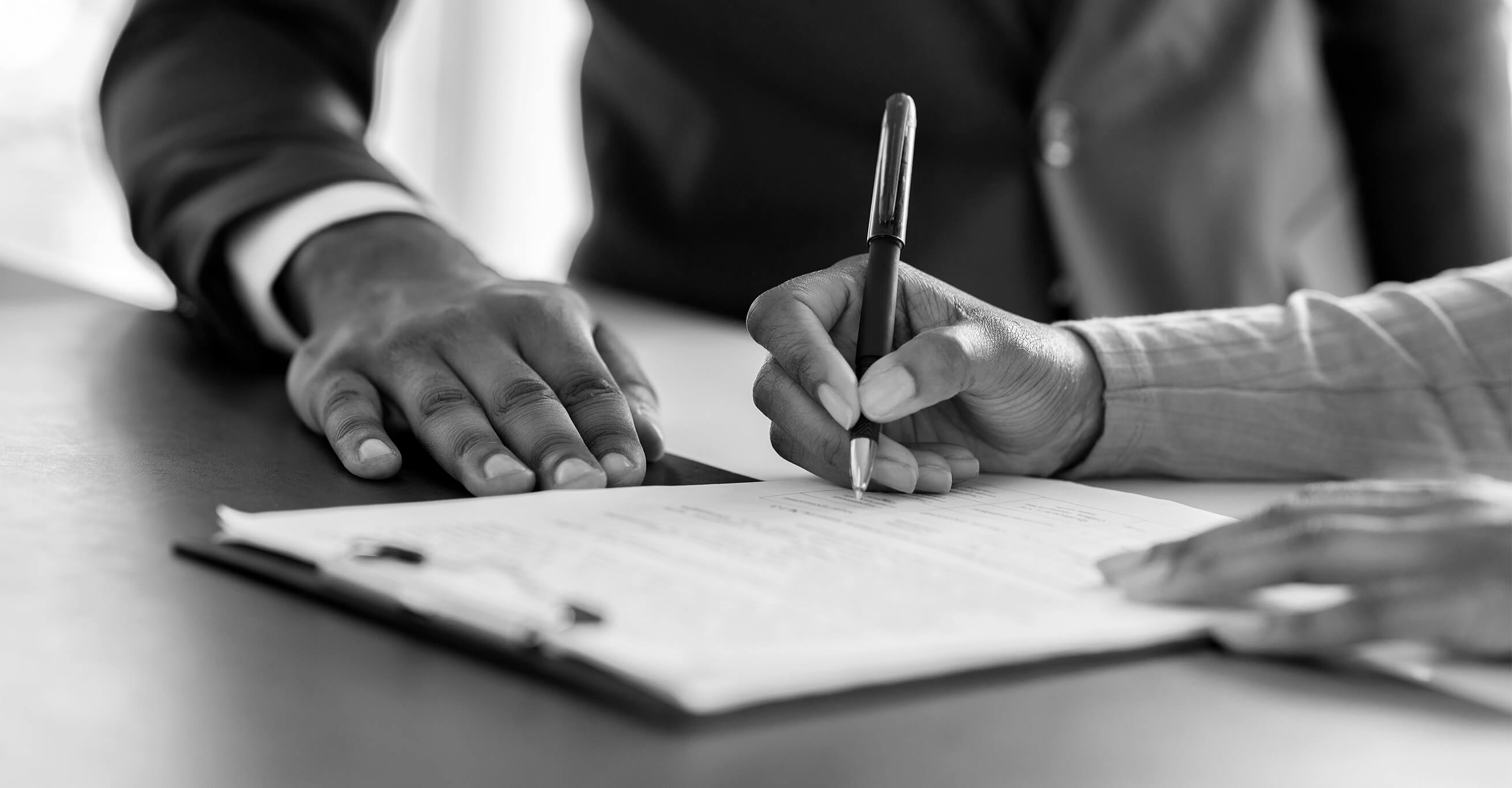 A client signs their final settlement agreement with their lawyer by their side, getting a firsthand answer to the question, “How long does a settlement take?”