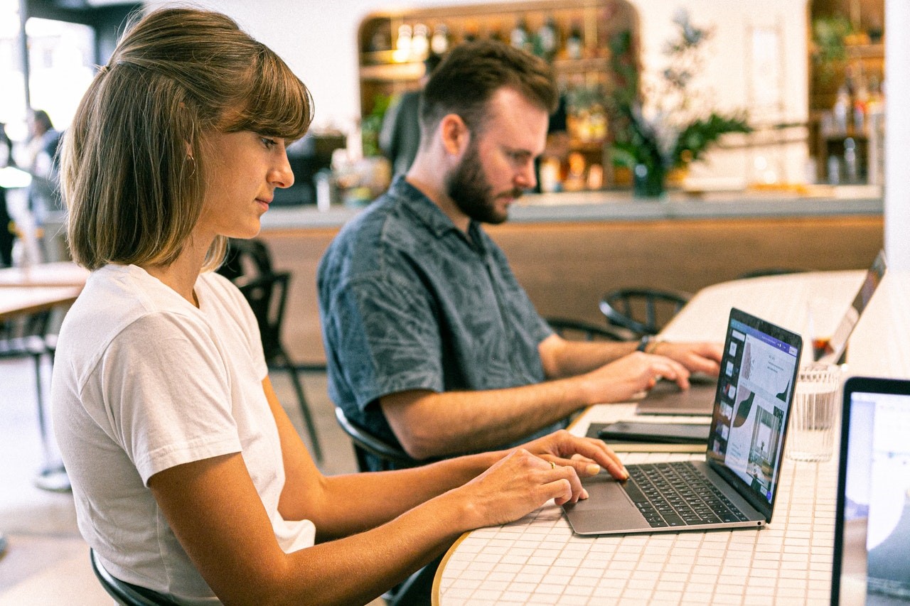 Two people sitting at a table in front of laptops