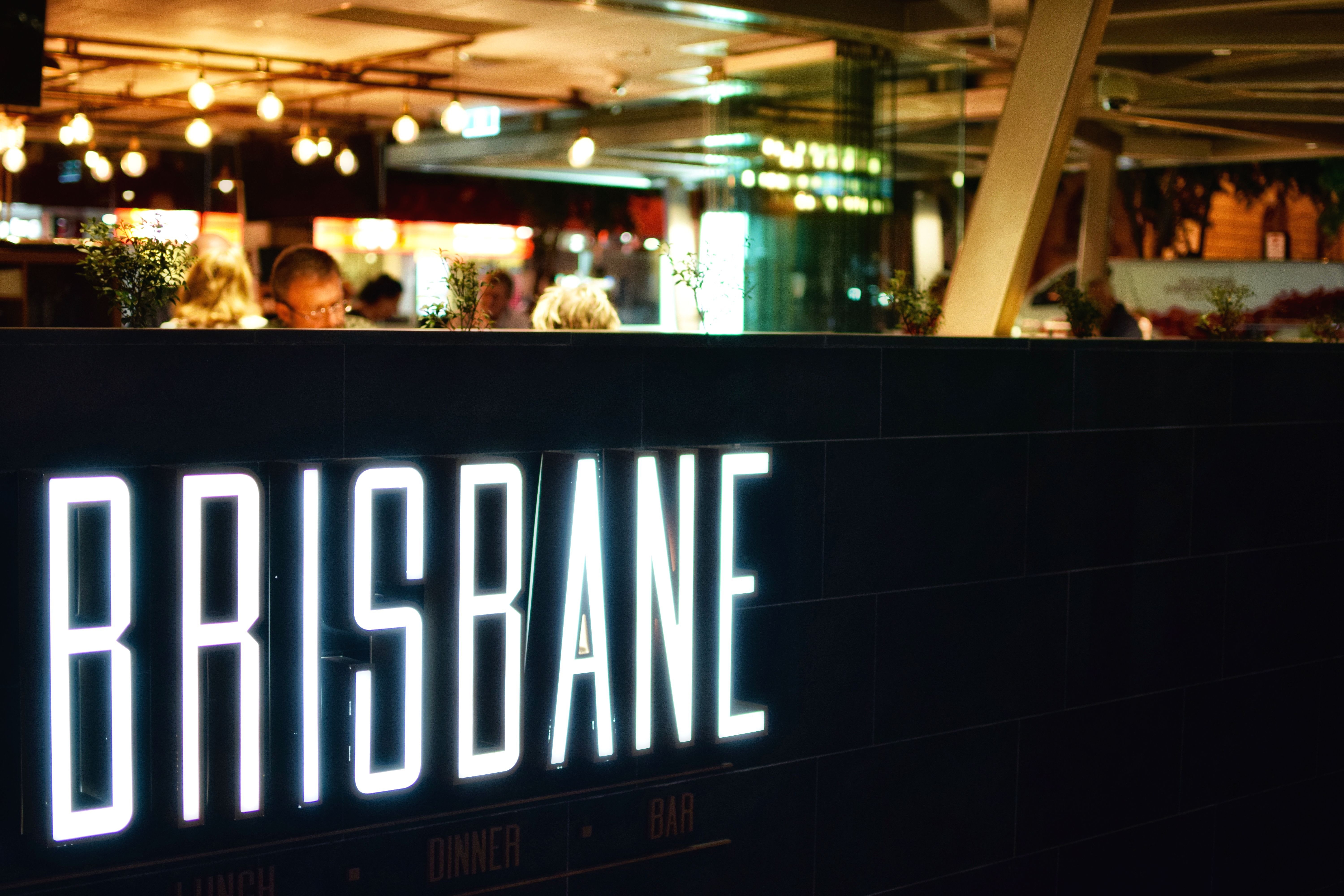 Diners sit inside a sports club with illuminated Brisbane sign oblivious to professional pest control services