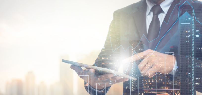 businessman using a tablet with blurred cityscape and financial graph in background