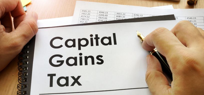 capital gains tax written on a piece of paper on top of financial documents