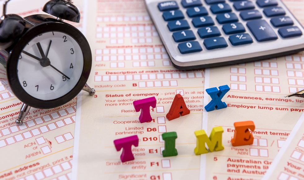 calculator and clock on top of annual australian company tax forms