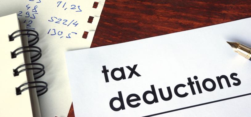 the phrase tax deductions written on paper beside financial figures