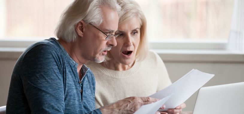 couple looking surprised whilst looking at company documents