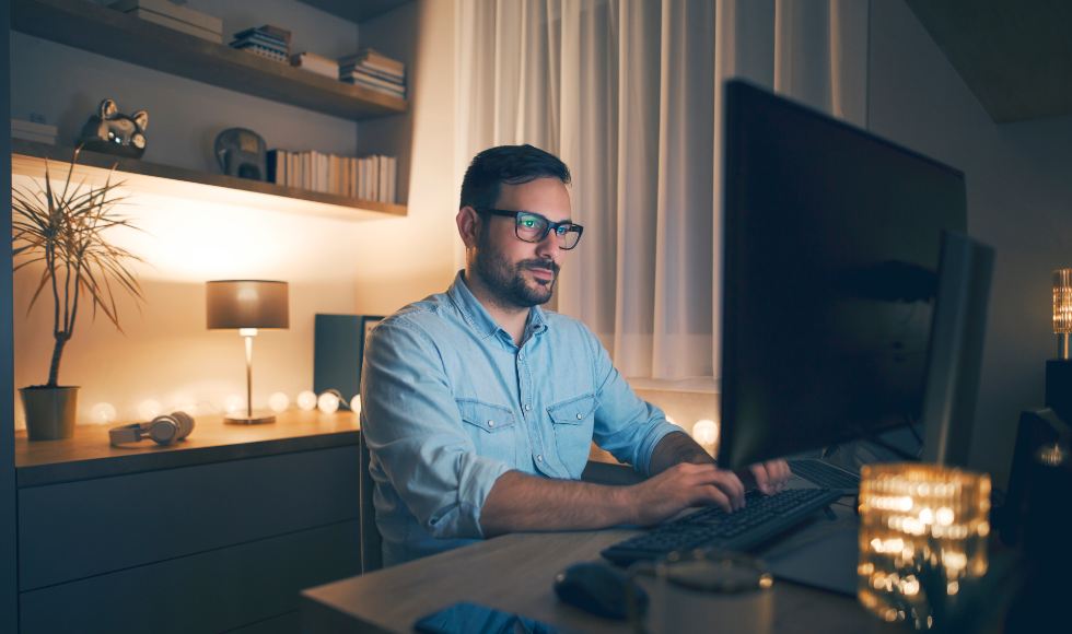 man working from home sitting at computer desk