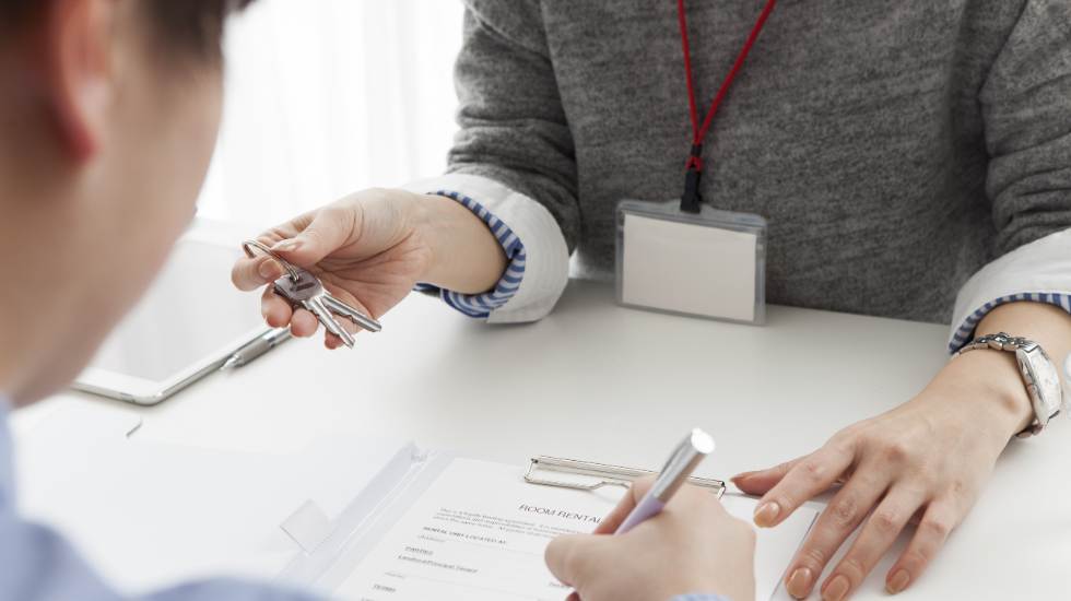 Woman holding keys man signing document