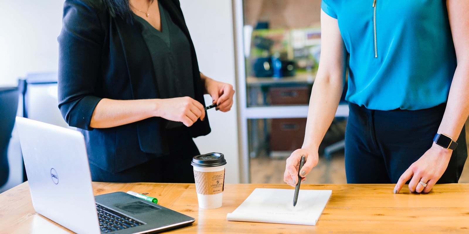 people standing at table with laptop