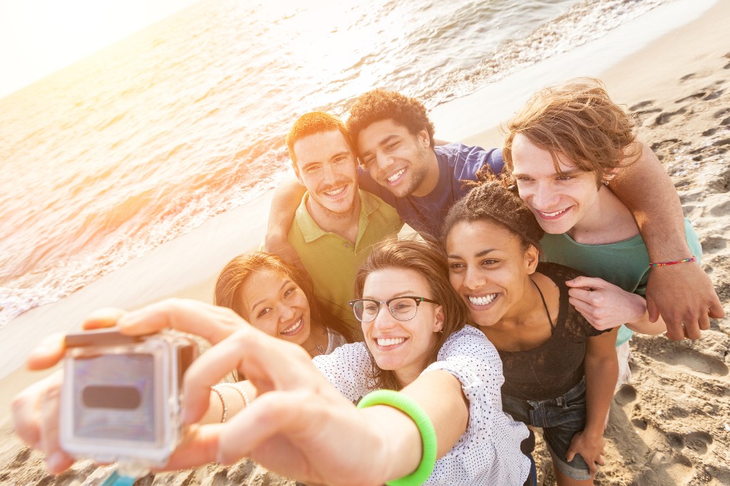 group of travelers taking selfie on the beach.