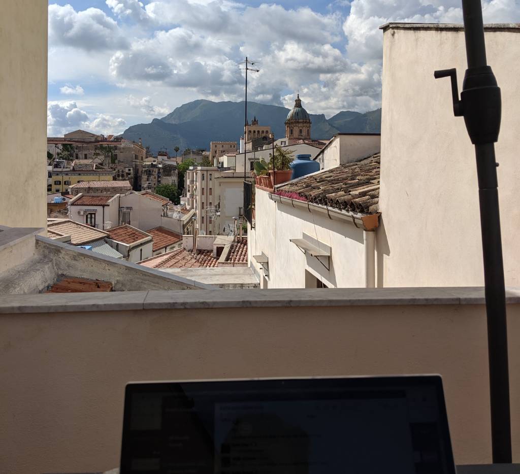laptop open in front of a view of Palermo street.