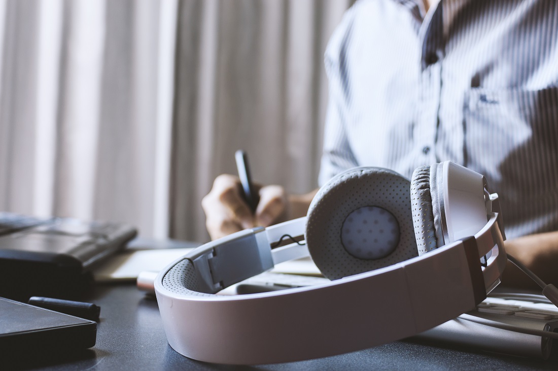 Headphones Resting on Desk Next to Worker