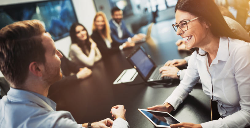 woman and man smiling at each other during company meeting