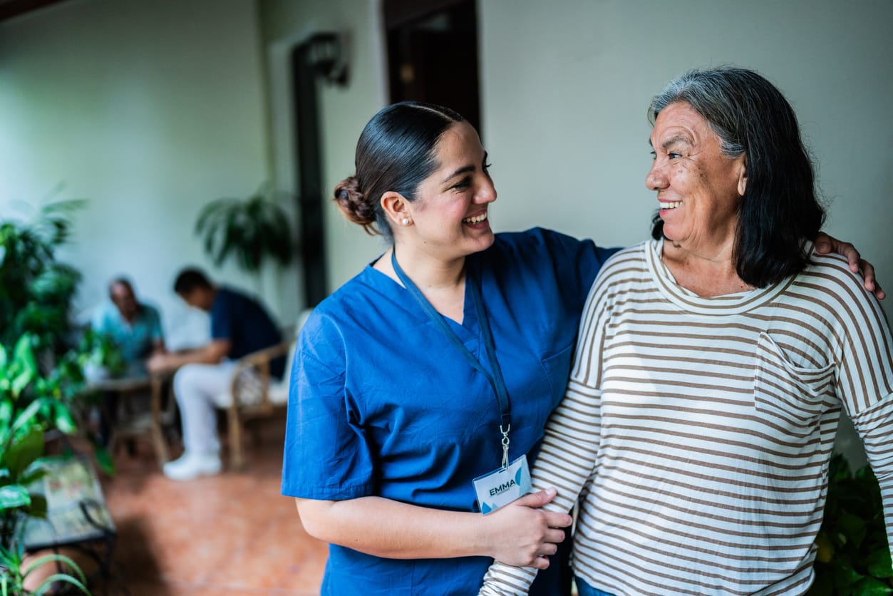 A CNA puts her arm around a nursing home patient and smiles. 