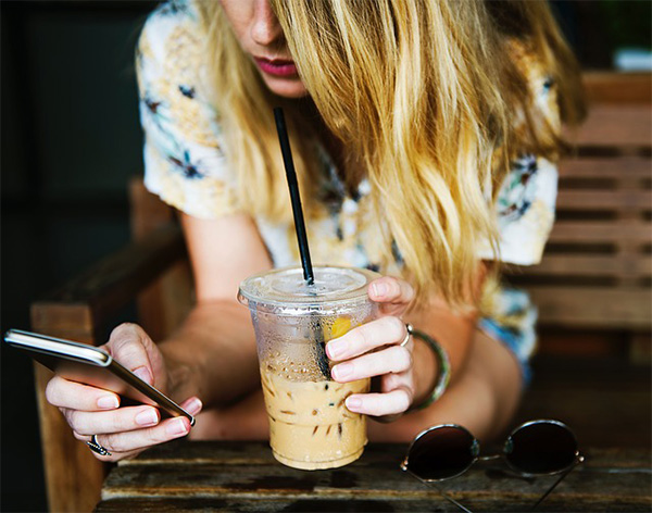 woman texting holding coffee
