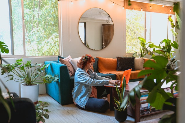 woman in living room typing on laptop