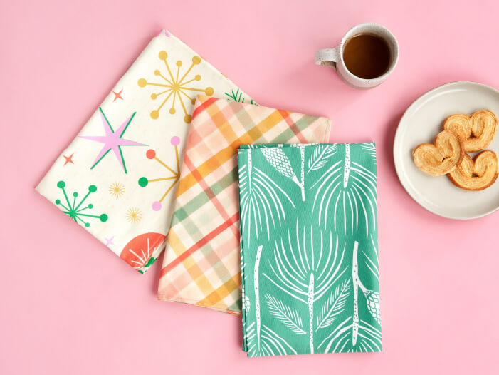 Festive pattern tea towels sit next to coffee and cookies