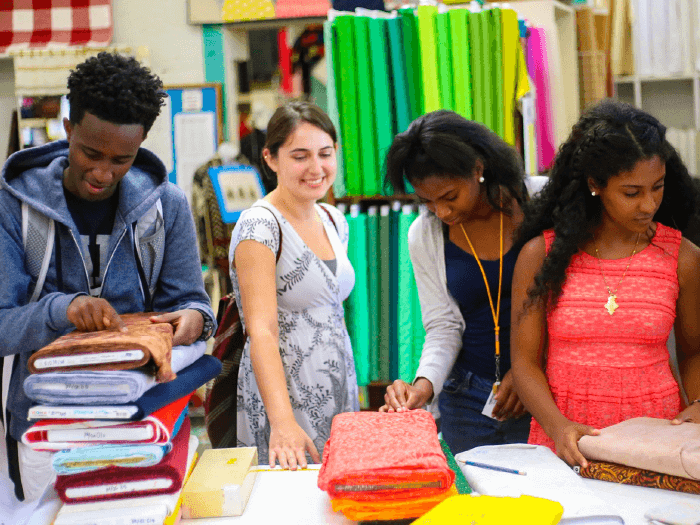 Students browse colorful fabric as part of a workshop