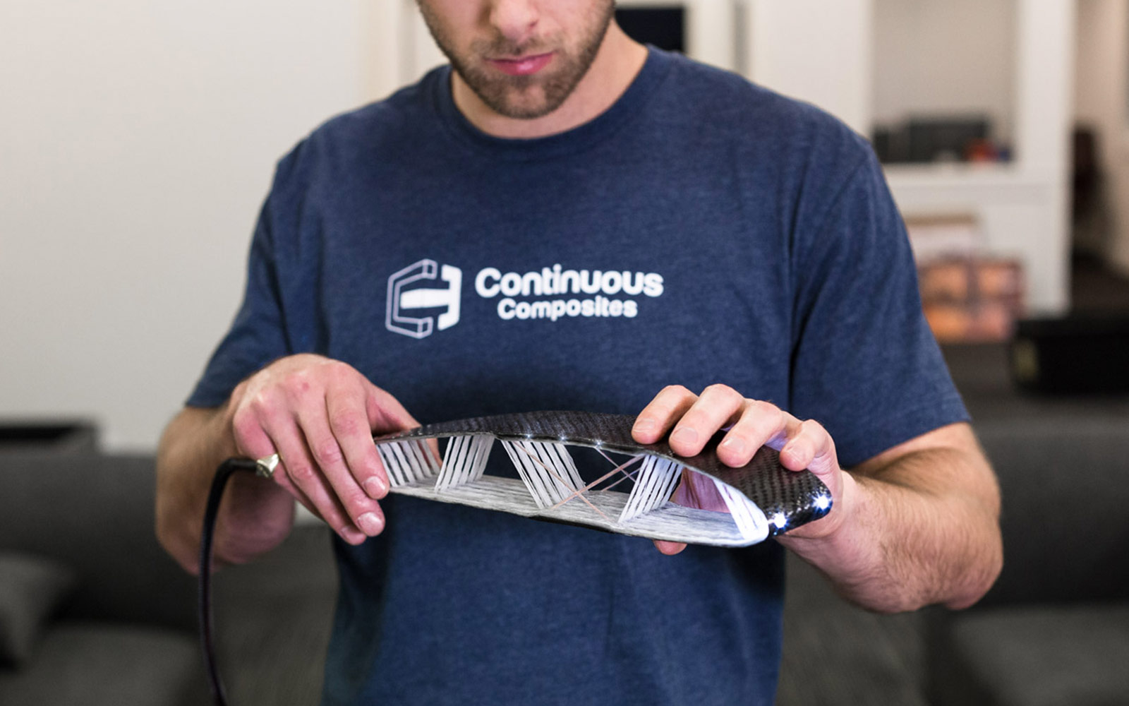 Team member holding embedded functionality airfoil with copper wire and fiber optics.