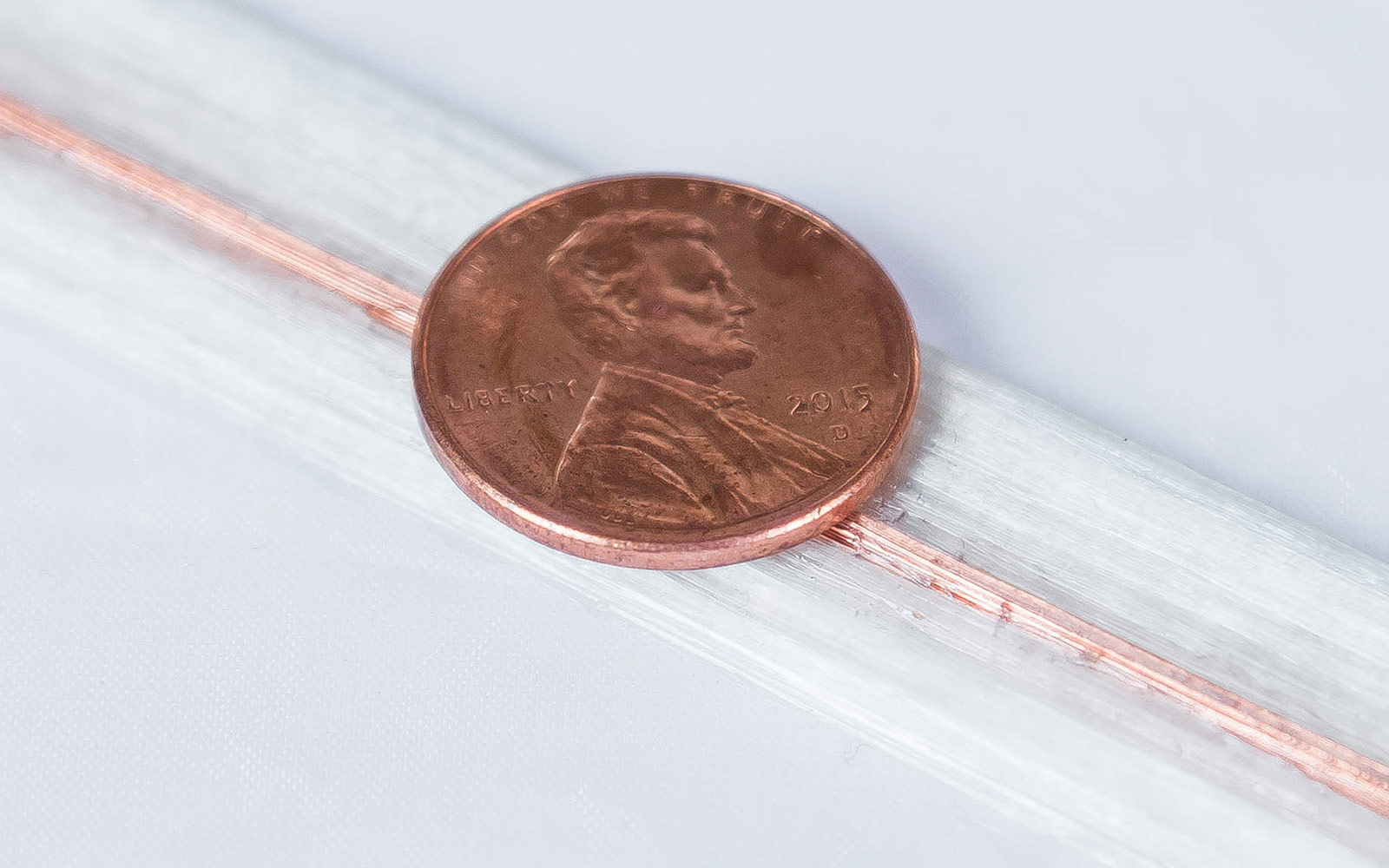 Fiberglass multi-channel print embedded with copper wire. A penny laid on top of print for scale.