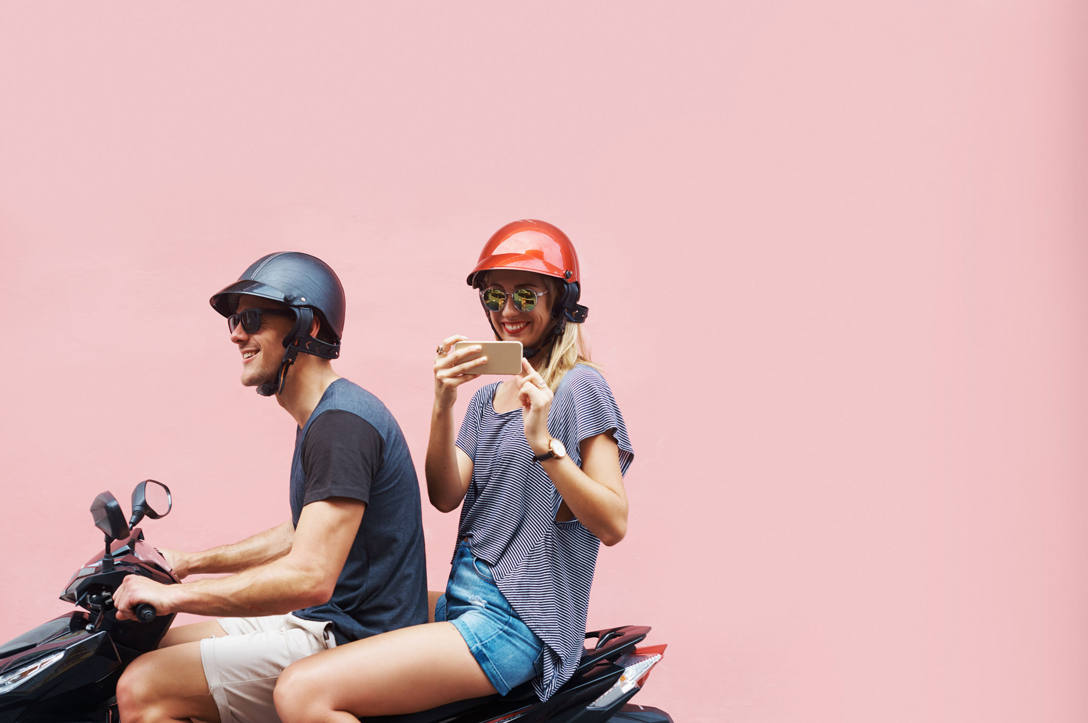 couple on scooter travelling pink background
