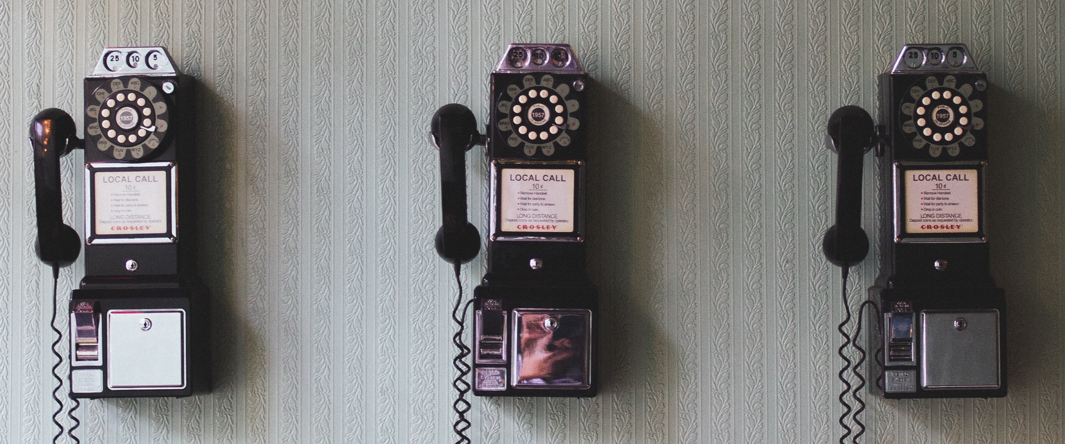 three old telephones hanging on the wall