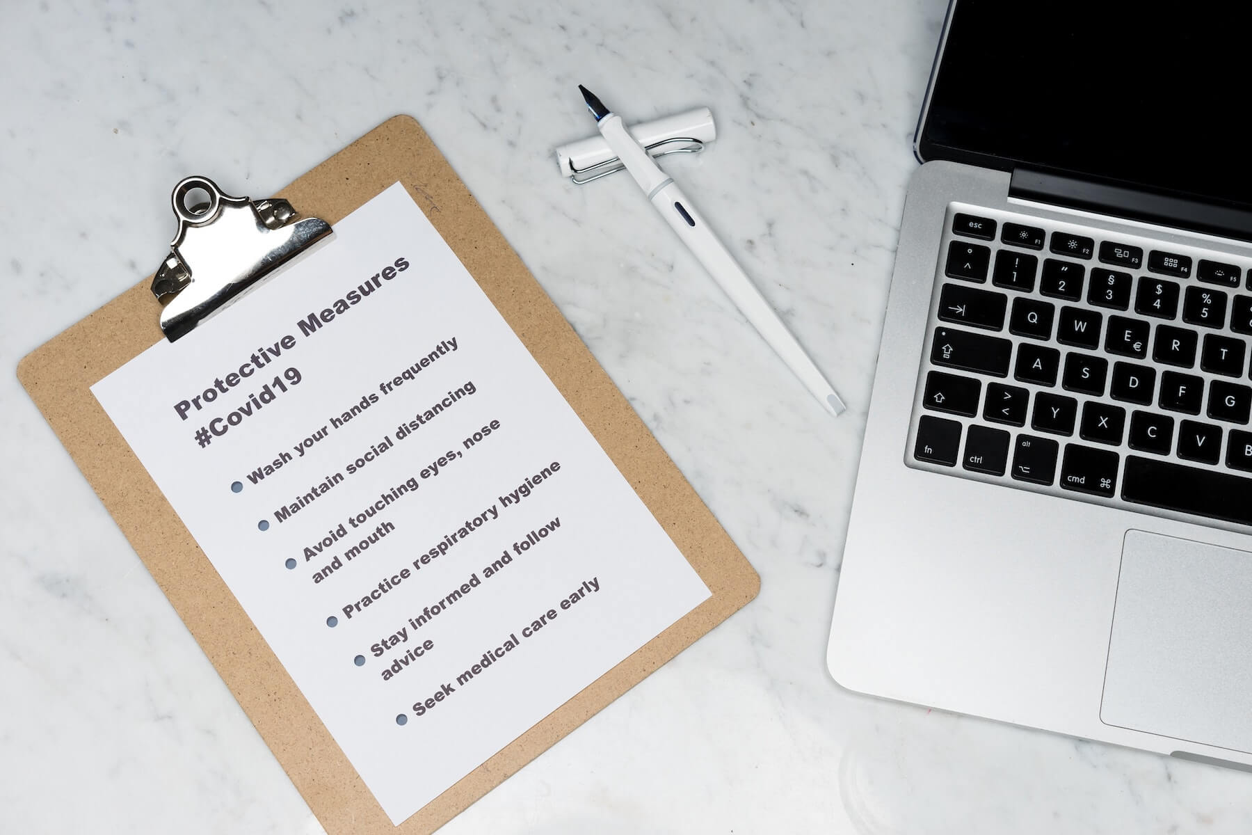 laptop and pen and clipboard with list of protective measures for covid19 on marble table nursing evidence based practice for nurses