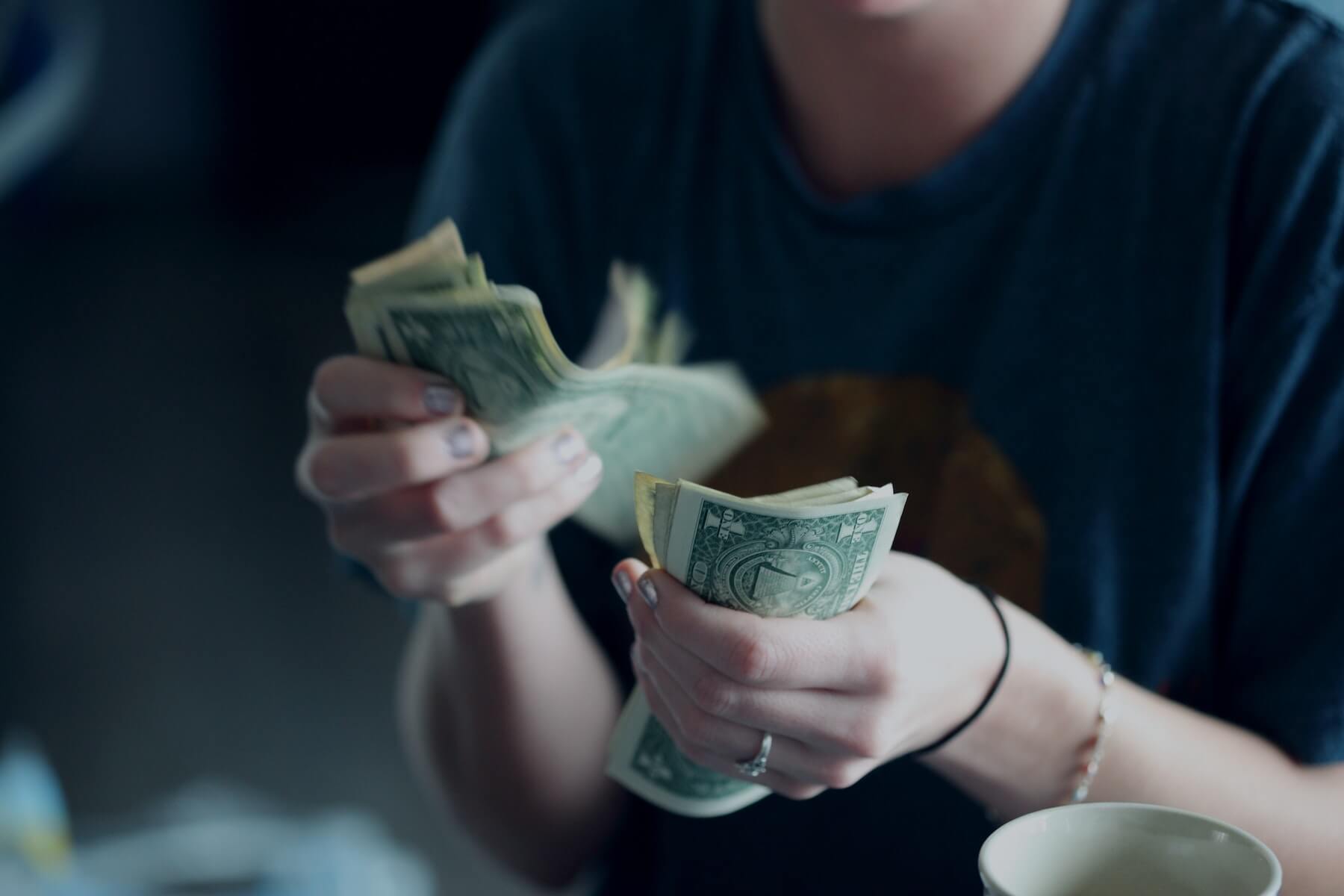 woman flipping through dollar bills after selling scrubs nursing side hustles