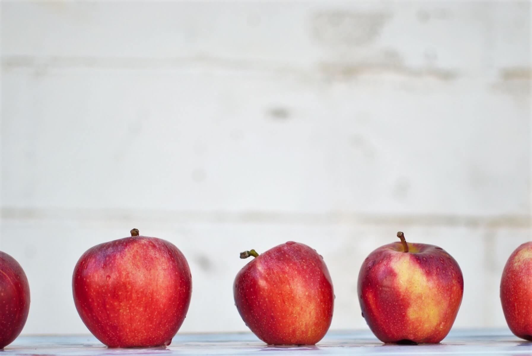 row of red apples on retaining wall with blurry wall in background school nursing