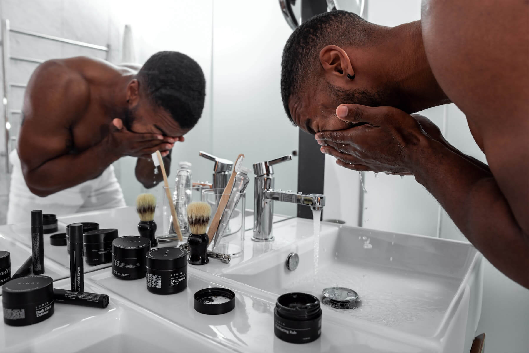 man washing face over sink with multiple skincare products around him skincare for nurses