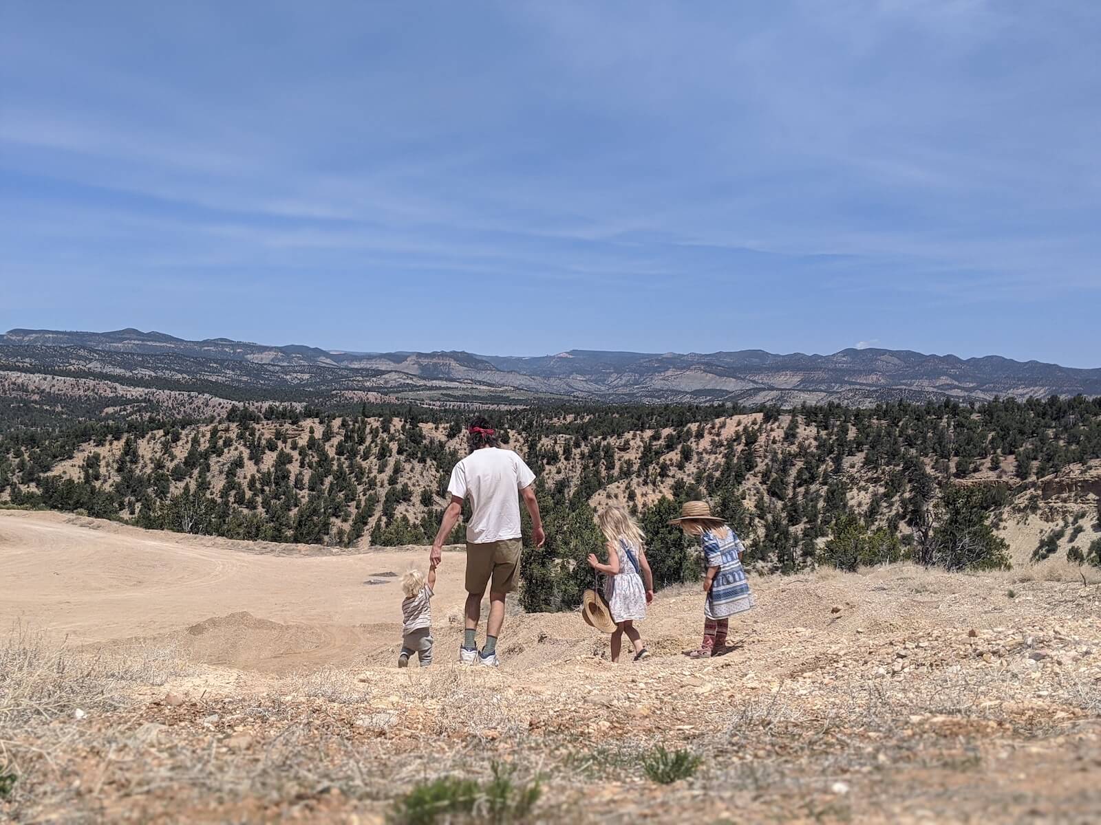 Russ Mortland RN and three kids hiking on dirt trail with trees in the background travel nursing in an RV