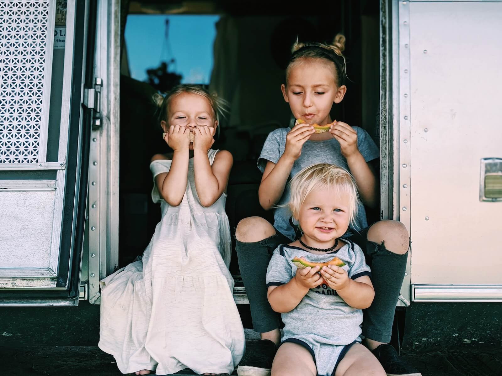 russ mortland children eating melon on the steps of their airstream travel nursing in an RV