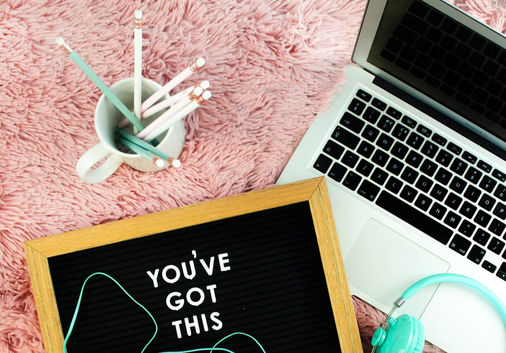 laptop notebook head phones and coffee mug with pencils in it sitting on pink carpet nursing cover letters